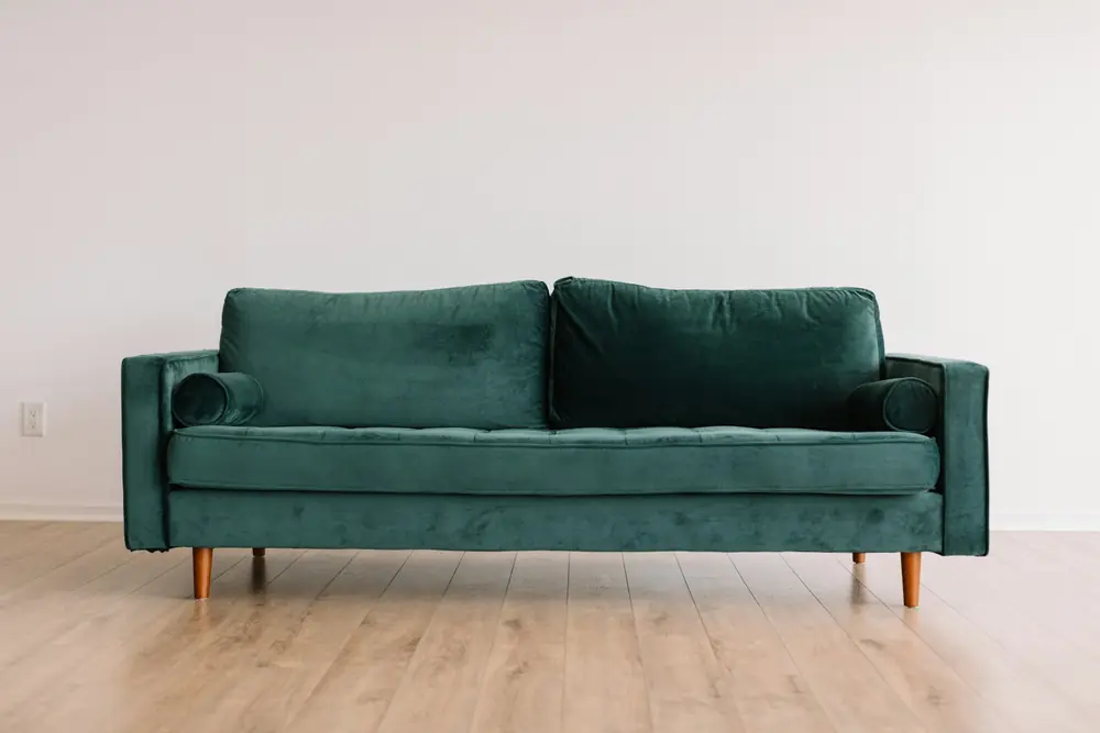 Green velvet couch in a bright room